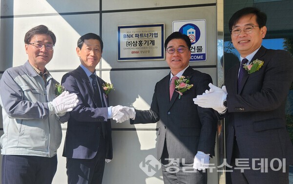 BNK경남은행 허종구 부행장(사진 오른쪽 두번째)과 ㈜삼홍기계 김홍범 대표 등이 파트너기업 현판 앞에서 기념촬영을 하고 있다. (사진제공=BNK경남은행)